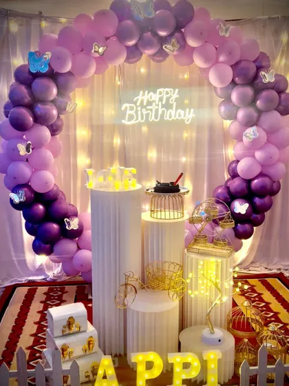 A still image of the purple butterfly-themed setup, highlighting the arrangement of the balloon arch, props, and marquee letters.