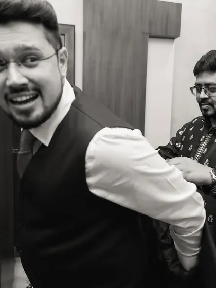 A fun, candid black and white shot of the groom getting help with his suit.