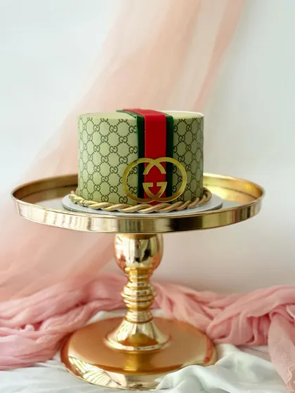 A cake for a fashion lover, wrapped in the iconic Gucci print. The edible logo and braided gold rope detail are crafted from fondant.
