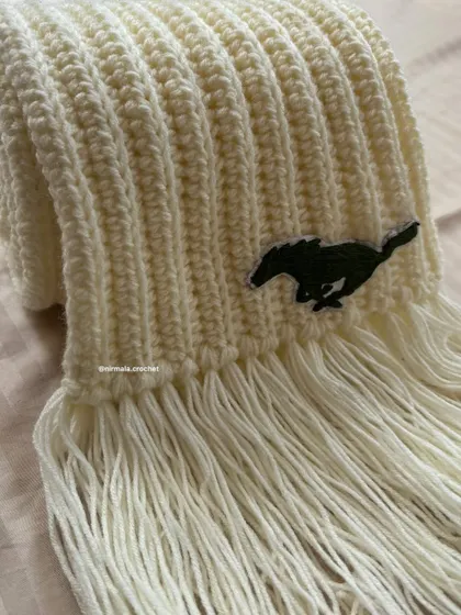 A close-up of the custom embroidered Mustang logo on our cream ribbed muffler. We take care to get the details just right for every personalized order.