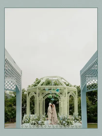 A wide shot of the wedding ceremony in Dehradun. The beautiful pastel-colored gazebo and the stunning mountain backdrop create a picturesque and serene setting for the couple's vows.