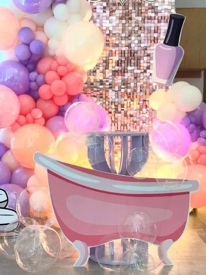 A tight shot on the spa party props, giving a clear view of the bathtub cutout and the clear "bubble" balloons at its base. This detail shot showcases the creative elements that make our themes unique.