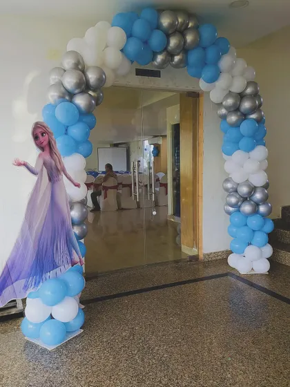 A Frozen-themed entrance arch in blue, white, and silver, with a life-sized cutout of Elsa to welcome guests.