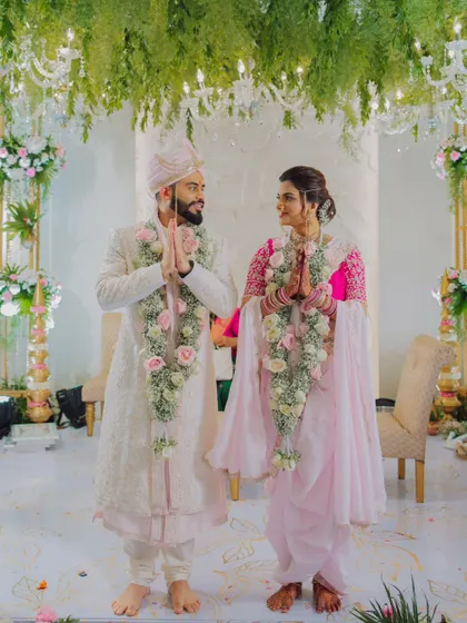 A full-length portrait of the couple in traditional Maharashtrian wedding attire, sharing a respectful 'namaste'.