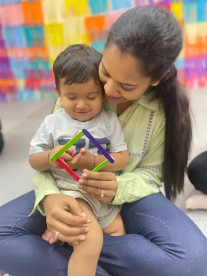 A mother and child share a tender moment while playing with colorful popsicle sticks, showing the emotional connection fostered during our classes.