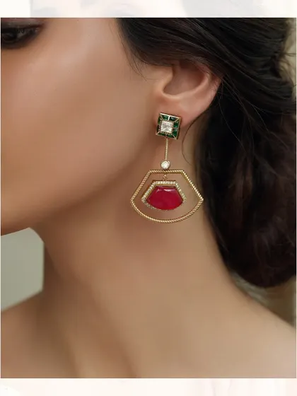 A pair of modern, geometric earrings with a fan-like shape, featuring a bold red stone.