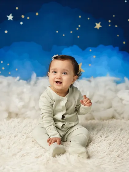 This little girl is sitting up proudly during her sitter session, set against a dreamy 'twinkle twinkle little star' backdrop. This stage is perfect for capturing their budding personality.