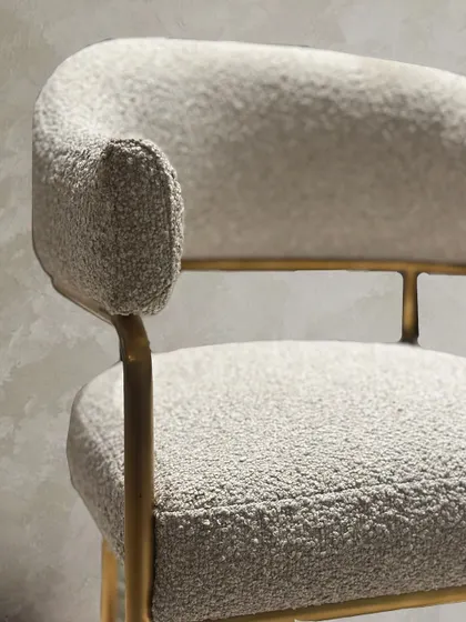 This macro shot emphasizes the quality of the bouclé fabric and the clean execution of the upholstery. The texture of the fabric becomes a primary design element, adding visual interest to the minimalist form.