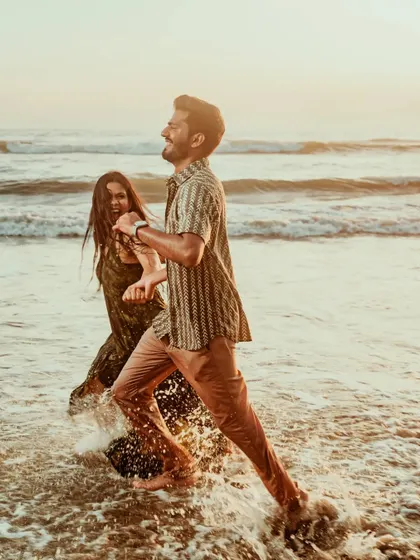 A couple runs through the waves at a Goan beach, splashing and laughing. This action shot is full of energy and perfectly captures the feeling of a carefree beach romance.