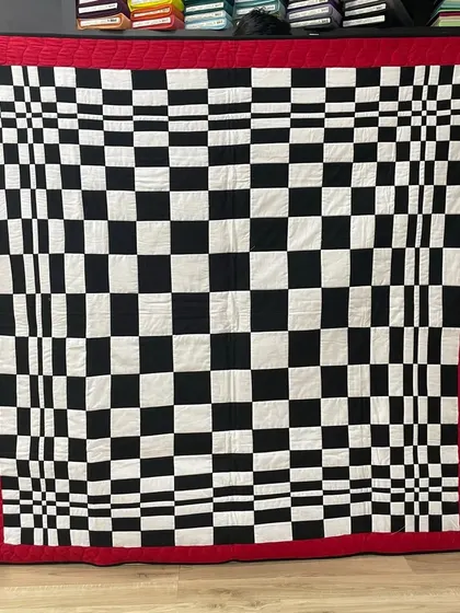 A mind-bending optical illusion quilt. The checkerboard pattern is manipulated to create a sense of three-dimensional space and movement.