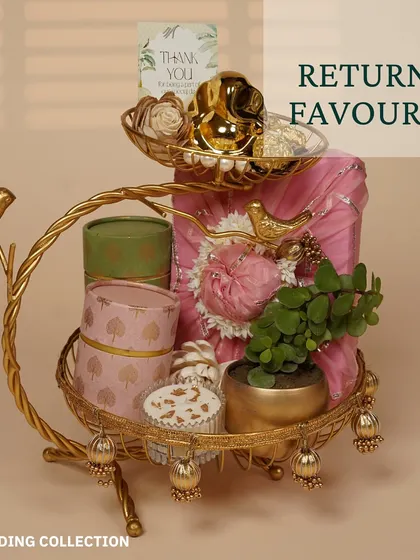An elegant return favor arrangement on a golden two-tiered stand. It features beautifully packaged gifts, a small plant, and a thank you card for guests.