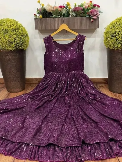 Our purple sequin gown displayed on a hanger, showing the pleated texture and ruffled hem.