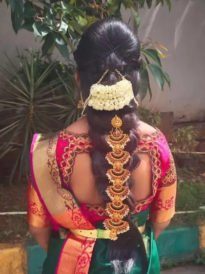 A simple yet elegant non-bridal hairstyle. This look features a traditional braid decorated with beautiful gold accessories and a string of jasmine, perfect for attending a wedding or festival.