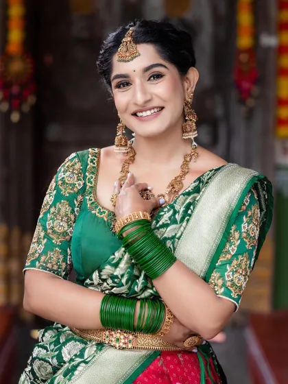 A happy client in a traditional green and red half saree, a classic combination for weddings.
