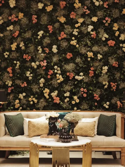 A luxurious photo-op area with a sofa set against a dense wall of flowers, creating a stunning and opulent backdrop for guest photos.