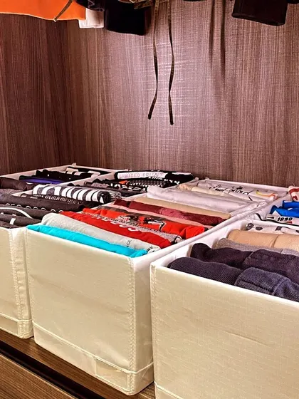 A top-down view of a drawer organized with file-folded t-shirts in bins. This is a perfect example of how to create a "drawer" system on a shelf.