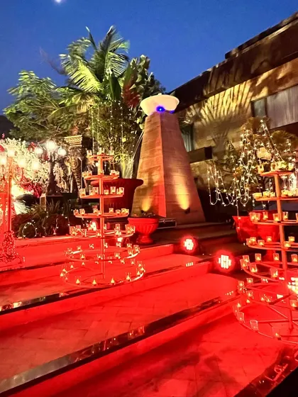Lighting is key to creating ambiance. Here, a red carpet is flanked by tiered candle displays and fairy lights, leading guests into the venue with a warm and inviting glow.