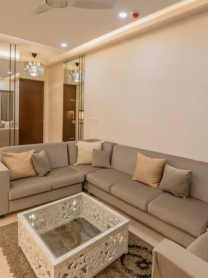 We use mirrors strategically to make spaces feel larger and brighter. In this living room, a large mirror panel reflects the seating area, adding depth and light to the room.