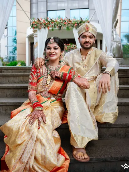 A relaxed and happy portrait of the couple sitting on steps, looking comfortable and in love in their traditional wedding attire.