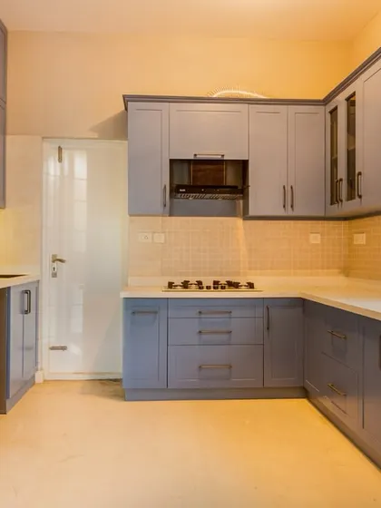 This kitchen combines functionality with style, featuring muted dusty blue cabinetry, sleek white countertops, and warm under-cabinet lighting for a clean and organized space.