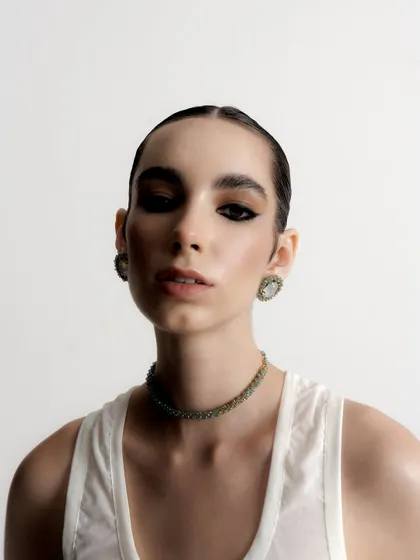A direct and powerful portrait that gives a clear view of the intricate choker and earring set. The model's intense gaze adds to the strength of the image.
