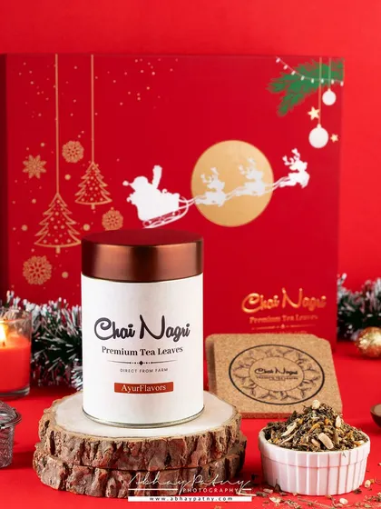 This Christmas-themed tea packaging shot is styled to look like a perfect holiday gift. The warm glow from the candle and the festive red box create a cozy and inviting winter scene.