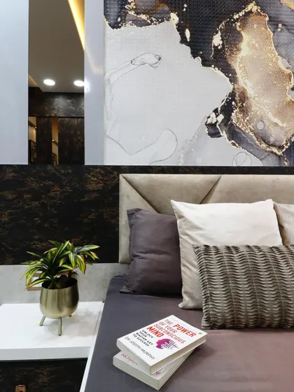 A close-up detail of the bedside area, showing the texture of the headboard, the abstract wallpaper, and the elegant side table. This highlights the quality of materials and finishes used.