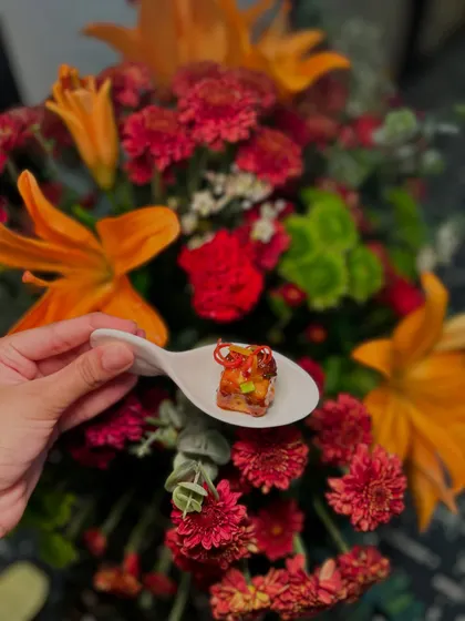 A single, perfect bite of an Asian-style cottage cheese appetizer, served on a ceramic spoon.