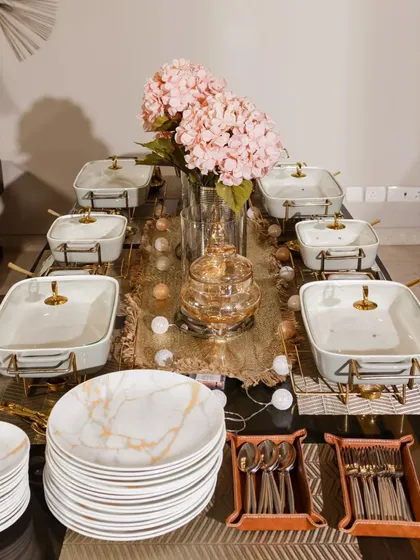 A full view of a stunning Diwali table setting. The combination of marble-patterned plates, gold-accented serving dishes, and soft pink hydrangeas creates a picture-perfect scene for a festive dinner.