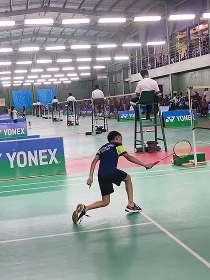 A player stretches for a difficult backhand shot during a competitive match at the YONEX SUNRISE tournament.