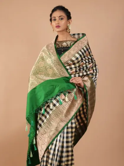 A classic black and white checkered Banarasi silk saree with a vibrant green and gold pallu. This is a bold and stylish choice for any fashion-forward woman.