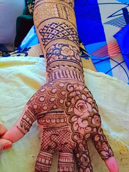 This design features a beautiful rose pattern on the palm, with the arm decorated in distinct bands of geometric and floral work. It's a structured yet elegant style.