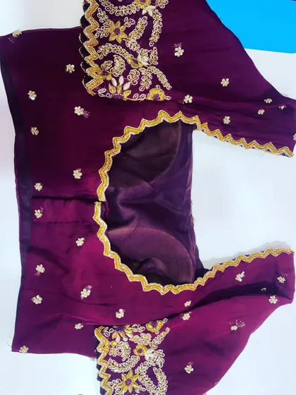 A simple purple blouse with a scalloped neckline. The sleeves have small gold embroidery motifs for a subtle, elegant look.