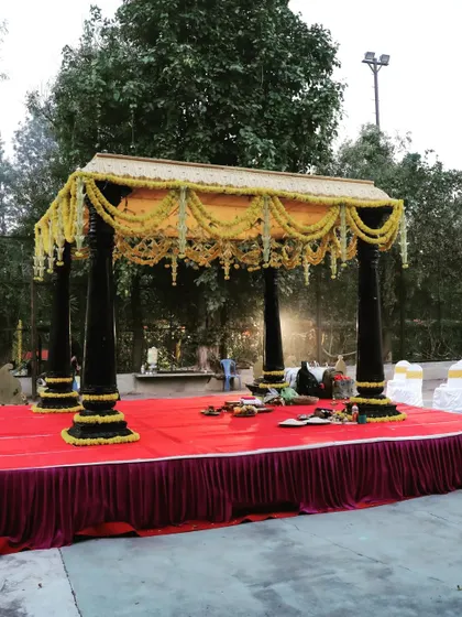 I constructed this classic outdoor wedding mandap at Chairman's Jade resort, blending traditional design with natural surroundings. The structure features dark wooden pillars, a canopy decorated with yellow marigolds, and a raised platform covered in red carpet for the ceremony.