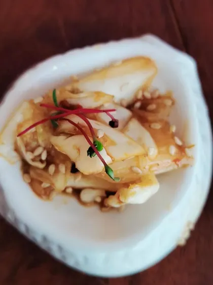 A beautifully composed salad with sesame seeds and micro-amaranth, served in a shell-shaped dish. We pay close attention to texture, flavor, and presentation in every dish.