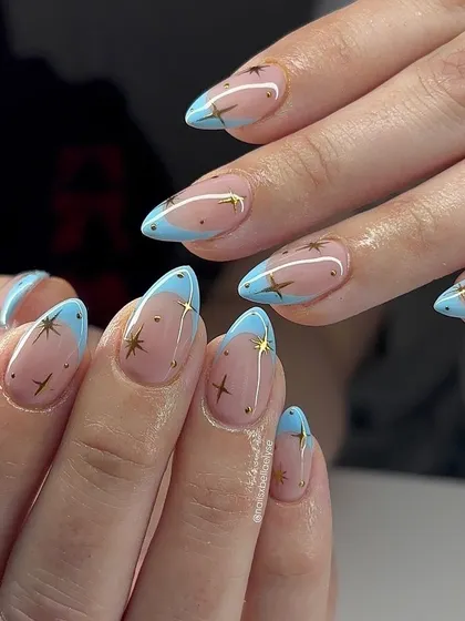 A dreamy, celestial-themed design. We hand-painted tiny gold stars over a baby blue French tip for a look that's perfect for stargazing on a clear night.