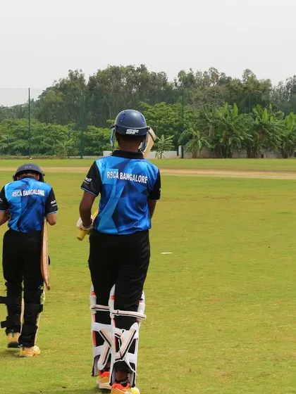 Two young batters walk out to the middle to start their innings in a Dasara Cup match.