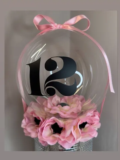 This hot air balloon hamper uses a silver bucket as the base, filled with beautiful pink artificial flowers. The balloon is personalized with the number 12 for a special birthday celebration.