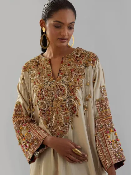 A close-up of the stunning handwork on the beige kurta. The multi-colored threads and beadwork create a piece of wearable art.