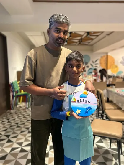 A father and son with their ocean-themed painting. The workshop allows for individual creativity while sharing the experience.