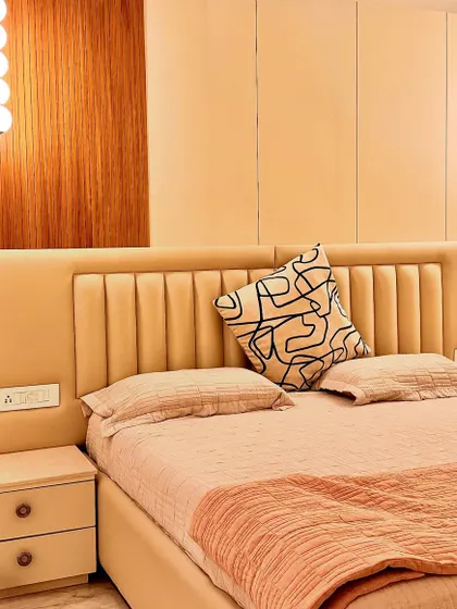 A detail shot of the bedroom's headboard, showing the vertical tufting that adds a subtle decorative element. The combination of soft textures and warm lighting is key to creating a calm and restful sleeping environment.