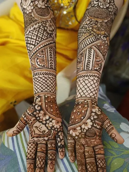 This design features a personalized touch with a name hidden in the palm. The arms are decorated with bands of different traditional patterns, creating a rich tapestry of henna art.