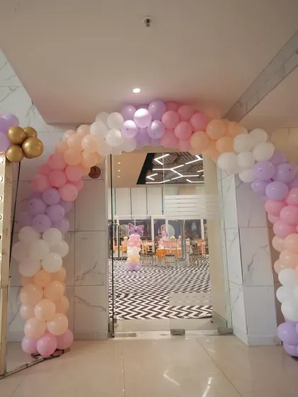 The entrance to Sia's butterfly party, featuring a pastel balloon arch and a welcome sign with a lit-up frame.