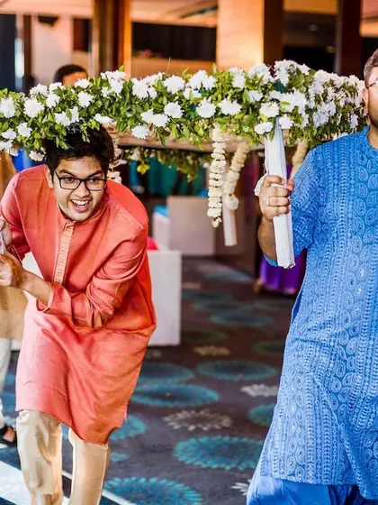The bride's brothers, with playful expressions, carry the 'phoolon ki chadar' during her entrance, a moment of sibling love and fun.