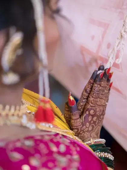 A close-up on the bride's hands in prayer, showcasing her intricate henna and the solemnity of the moment.