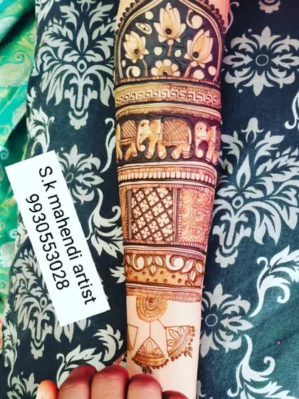 A close-up of an arm design showing bands of different patterns. You can see elephants, lotuses, and geometric jaali work, demonstrating a variety of techniques.