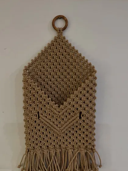 Keep your space organized with this handy macrame pocket wall hanging. It's perfect for storing mail, magazines, or other small items, and the wooden ring makes it easy to hang anywhere.