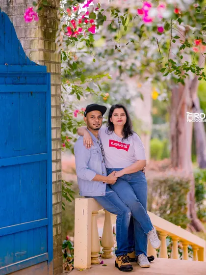 A relaxed and happy portrait of a couple on a balcony. Their casual denim outfits and the bright blue door create a fresh and modern look.