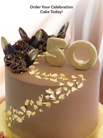 A close-up of the golden "50" and the beautiful contrast between the smooth chocolate frosting and the shimmering gold leaf.