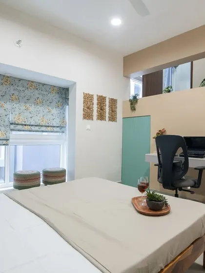 A guest bedroom designed with a loft space. The main floor features a simple wooden bed and a floating desk, while a small staircase leads to an upper level, maximizing the use of vertical space.